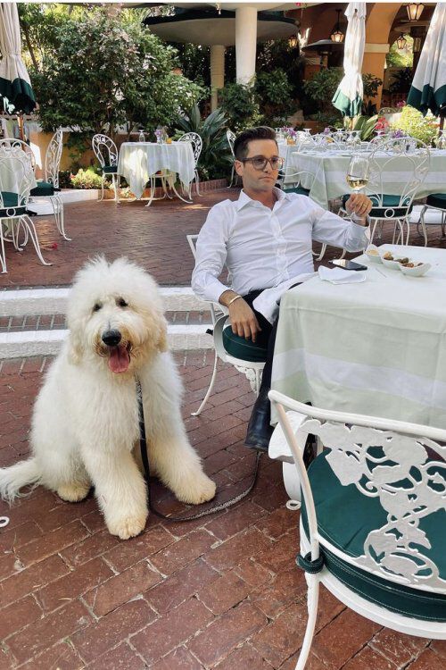 Josh Flagg sitting down with a white button up with his dog